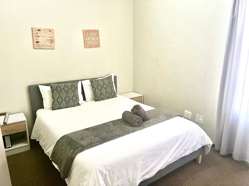 A well-maintained bedroom featuring neutral wall finishes, carpeted flooring, and integrated electrical points.
