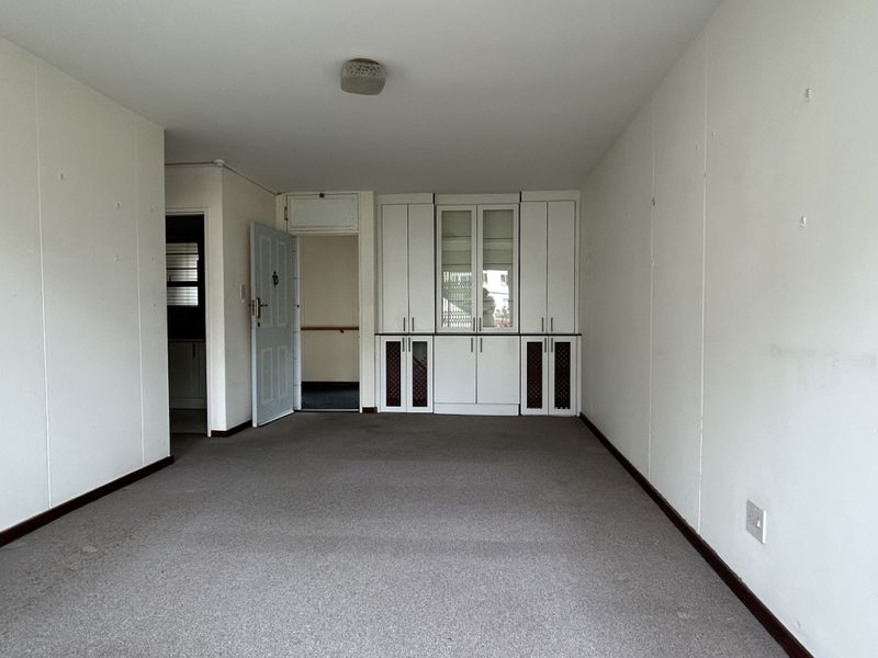 An empty living room featuring built-in cabinetry, carpeted flooring, and neutral wall finishes, offering a blank canvas for potential updates.