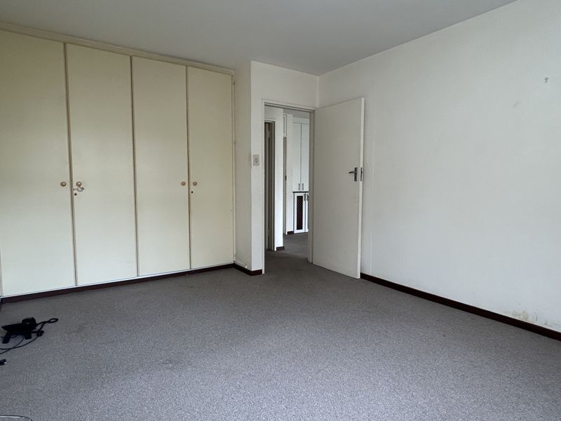 An empty bedroom featuring built-in cupboards, carpeted flooring, and a neutral interior, offering a blank canvas for potential updates and personalization.