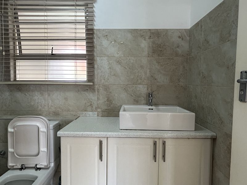 A functional bathroom featuring a vanity cabinet with a vessel sink, tiled walls, and a toilet, providing a clean and practical space.