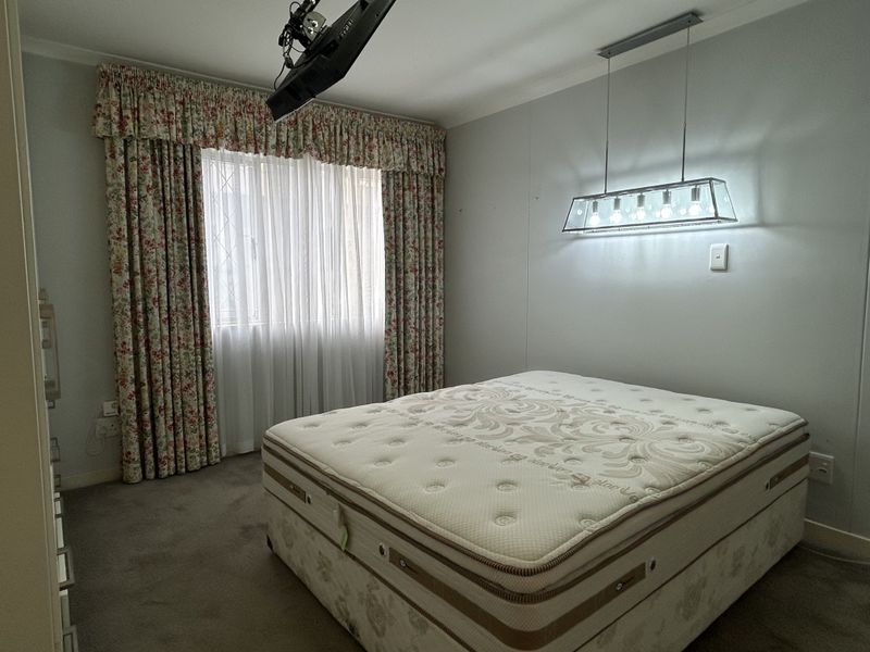 A bedroom featuring carpeted flooring, a fitted pendant light fixture, and window treatments with curtain tracks.