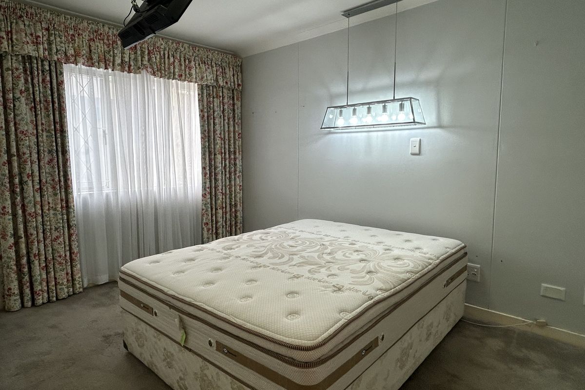 A bedroom featuring carpeted flooring, a central pendant light fixture, and window treatments. The space is ready for a modern update to its finishes.