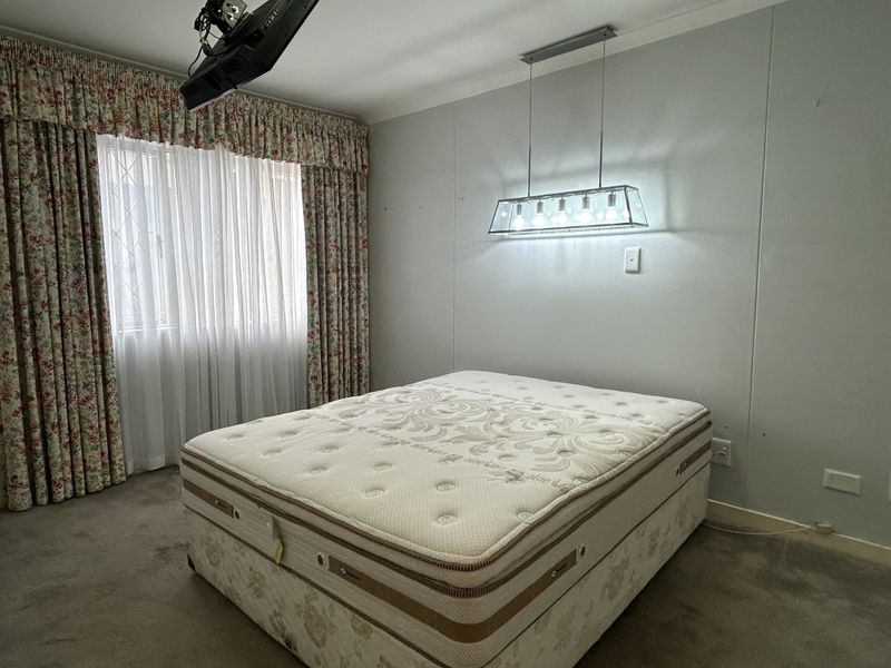 A bedroom featuring carpeted flooring, a central pendant light fixture, and window treatments. The space is ready for a modern update to its finishes.