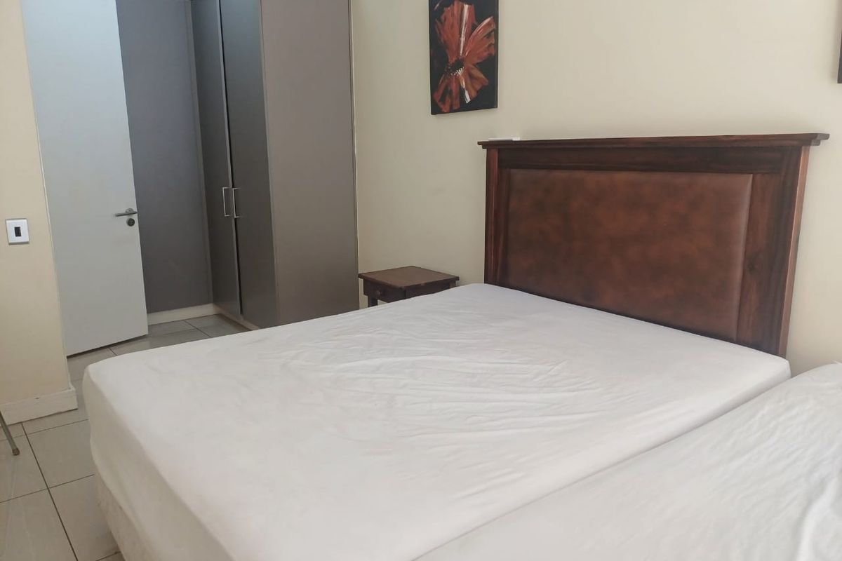 A well-maintained bedroom featuring neutral walls, tiled flooring, and a functional built-in wardrobe.