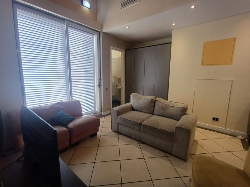 A living room featuring tiled flooring, built-in wardrobe storage, recessed lighting, and a sliding glass door providing access to the exterior.