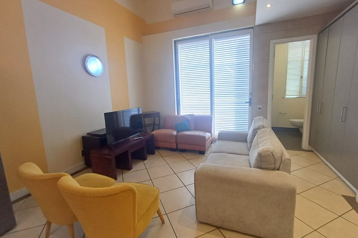 A living room featuring tiled flooring, a split-system air conditioner, and a sliding glass door leading to an outdoor area, with adjacent built-in storage.