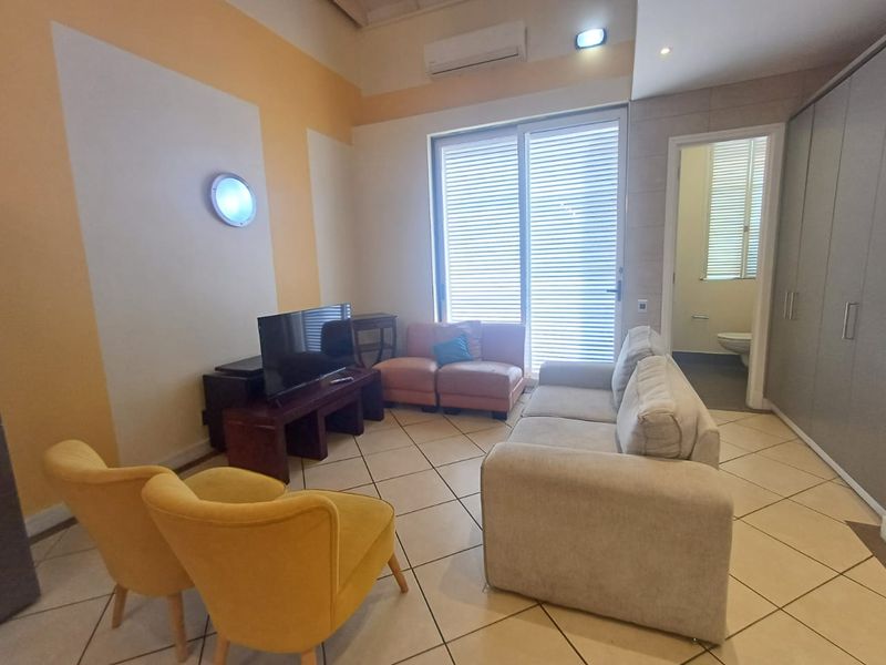 A living room featuring tiled flooring, a split-system air conditioner, and a sliding glass door leading to an outdoor area, with adjacent built-in storage.