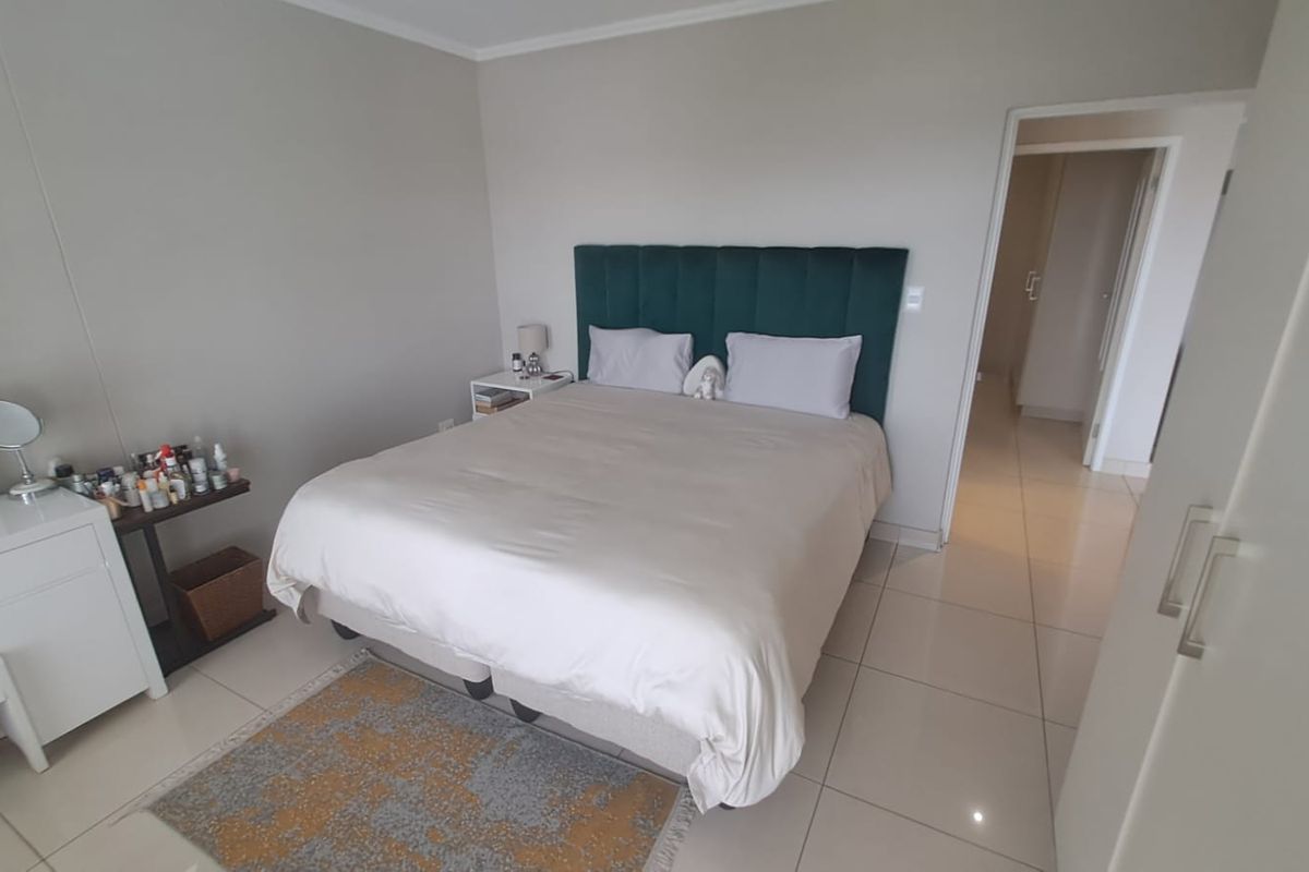 A well-maintained bedroom featuring neutral wall tones, tiled flooring, and a direct view into the adjacent hallway.