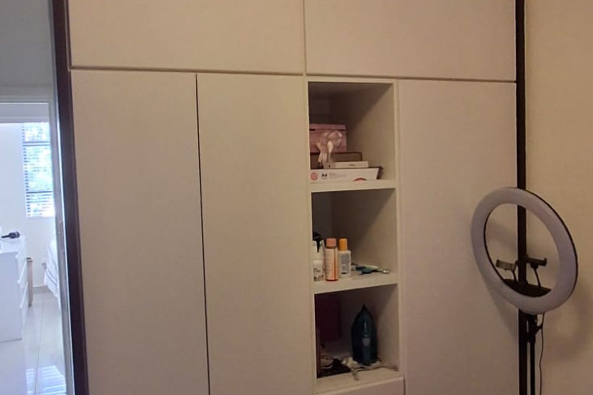 A bedroom featuring a large, modern built-in wardrobe with integrated shelving and neutral tiled flooring.