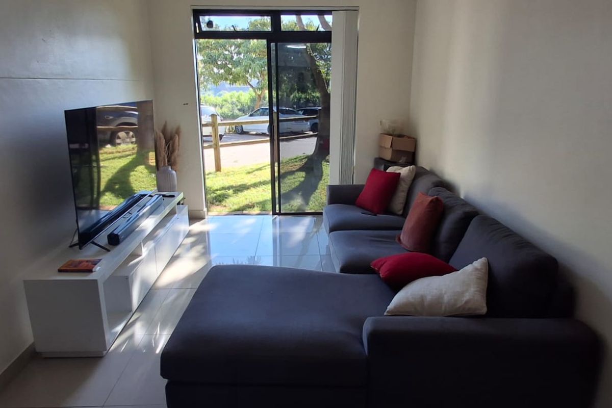 A living room featuring tiled flooring and a sliding glass door providing natural light and access to the exterior.