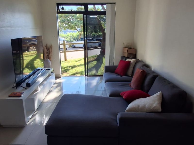 A living room featuring tiled flooring and a sliding glass door providing natural light and access to the exterior.