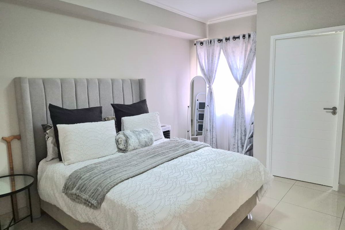 A well-maintained bedroom featuring neutral wall tones, tiled flooring, and a window with natural light.