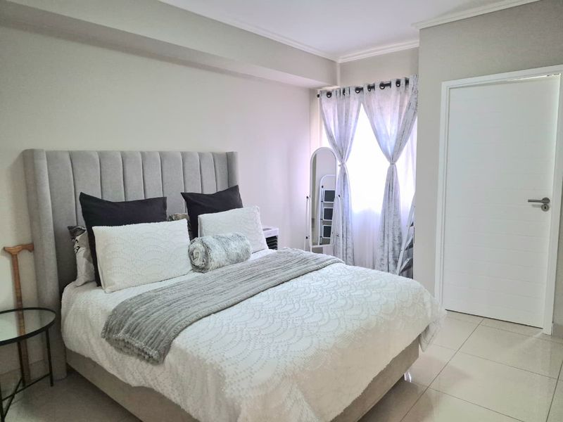 A well-maintained bedroom featuring neutral wall tones, tiled flooring, and a window with natural light.