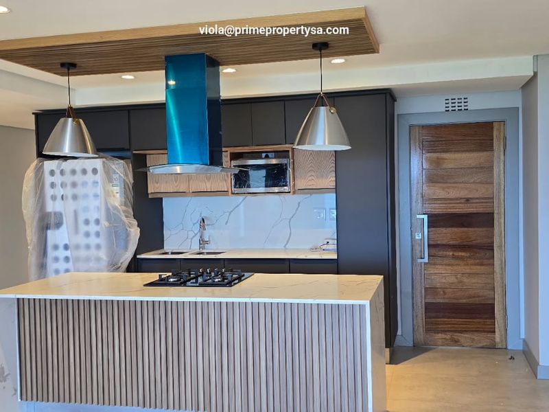 Modern kitchen featuring a central island with gas hob, stone countertops, timber slat detailing, and high-end integrated appliances in a contemporary open-plan space.