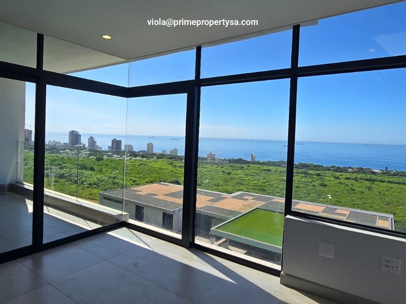 An expansive, empty interior space featuring floor-to-ceiling windows that offer panoramic ocean and coastal views.