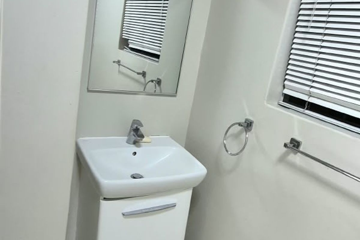 A clean and modern bathroom featuring a wall-mounted vanity with a ceramic basin, chrome fixtures, and neutral tiled flooring.