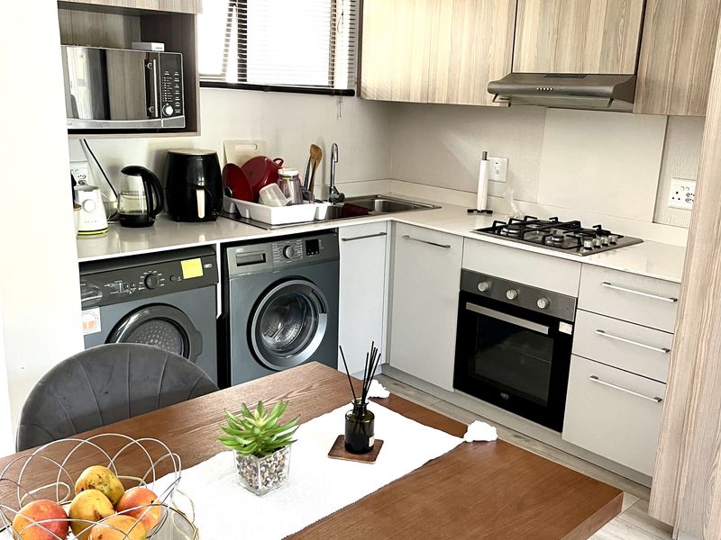 Modern open-plan kitchen featuring light wood-grain cabinetry, integrated appliances, gas hob, and built-in oven, seamlessly connected to the dining area.