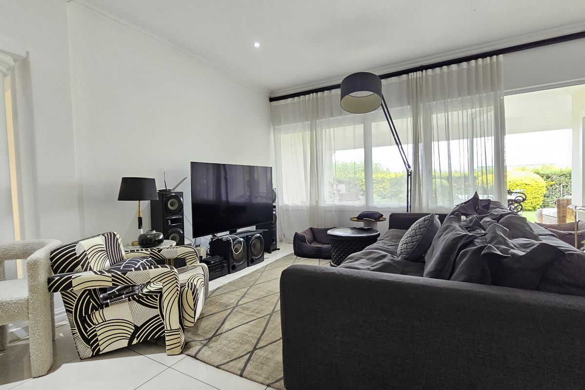 A bright and spacious living room featuring tiled flooring, recessed lighting, and large sliding glass doors that provide access to the outdoor area.
