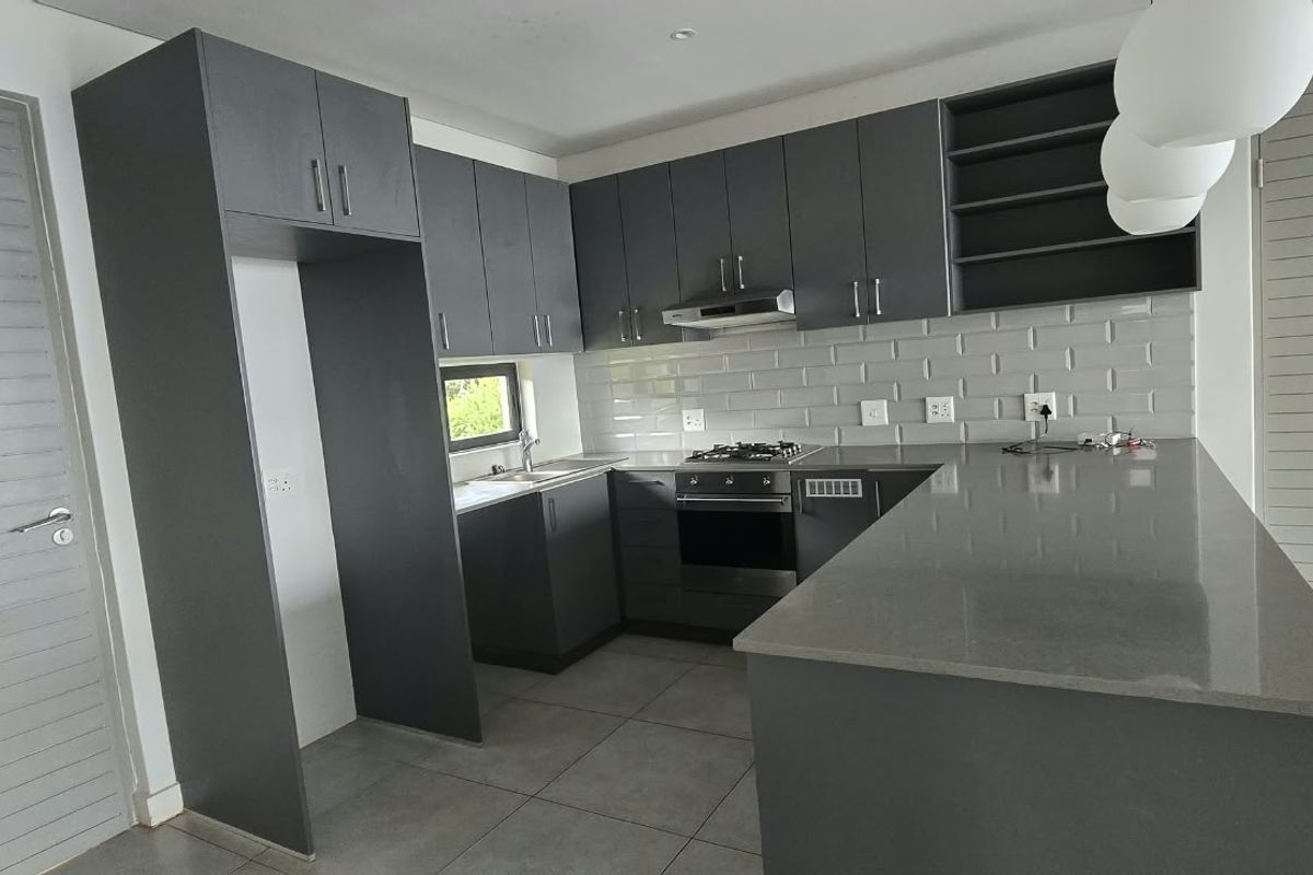 Modern kitchen featuring dark grey cabinetry, stone countertops, subway tile backsplash, built-in oven, gas hob, and a functional kitchen island.