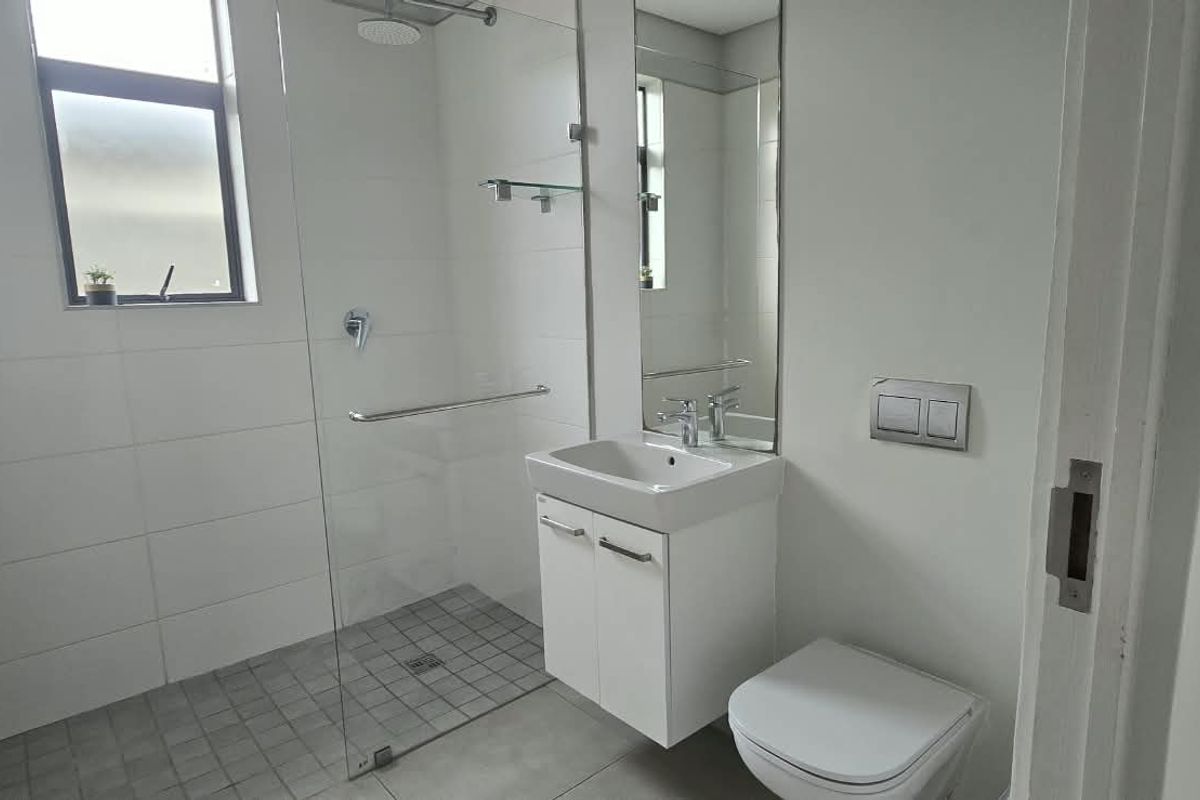 Modern bathroom featuring a walk-in shower with glass screen, wall-mounted vanity with basin, and a wall-mounted toilet with concealed cistern.