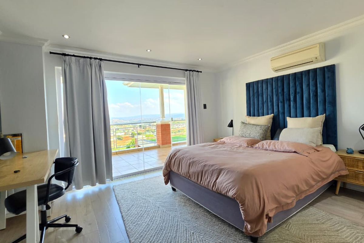 Spacious bedroom featuring laminate flooring, recessed lighting, and direct access to a private balcony with scenic views.