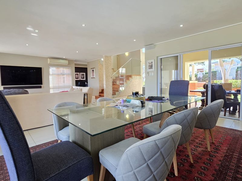 Spacious open-plan living and dining area featuring tiled floors, recessed lighting, and seamless access to the outdoor patio through large sliding glass doors.