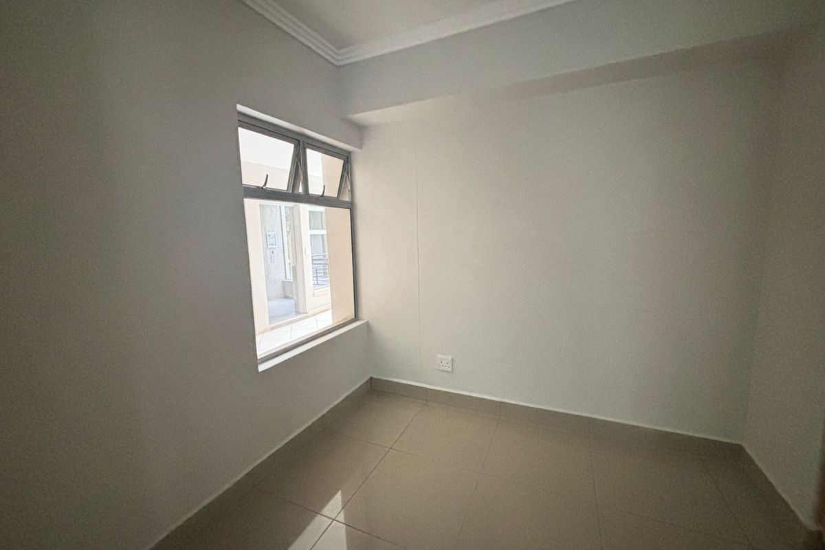 A clean, empty bedroom featuring neutral tiled flooring, white walls, and an aluminium-framed window, providing a blank canvas for personalization.