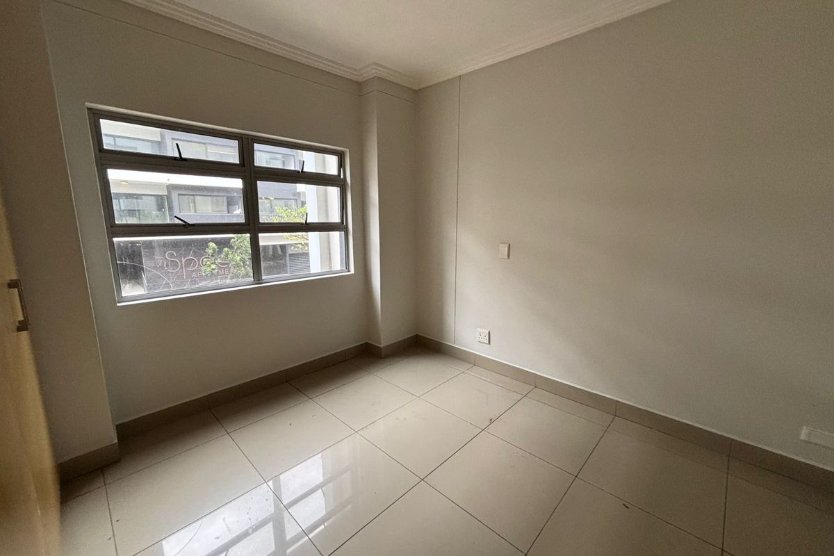 A clean, empty bedroom featuring neutral tiled flooring, large aluminium-framed windows, and minimalist finishes, ready for personalization.