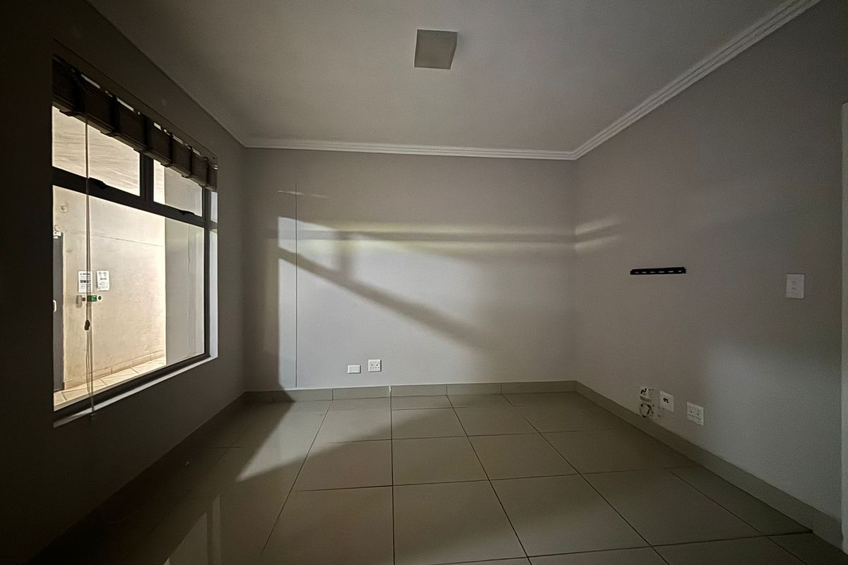 A clean, empty living area featuring neutral tiled flooring, cove cornicing, and integrated electrical and data points, ready for personalization.