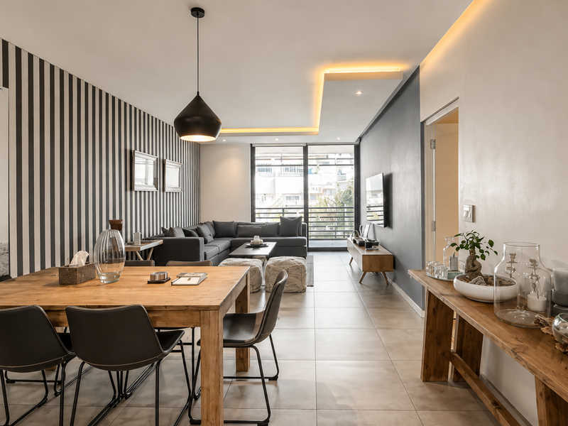 Modern open-plan living and dining area featuring tiled floors, recessed ceiling lighting, and a large sliding glass door leading to a balcony.