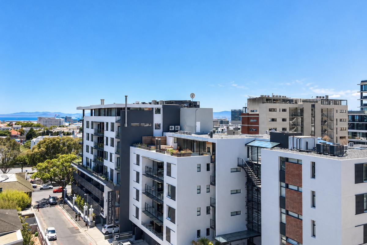Aerial view of a modern multi-story apartment complex featuring contemporary architecture, rooftop terraces, and surrounding urban street infrastructure.