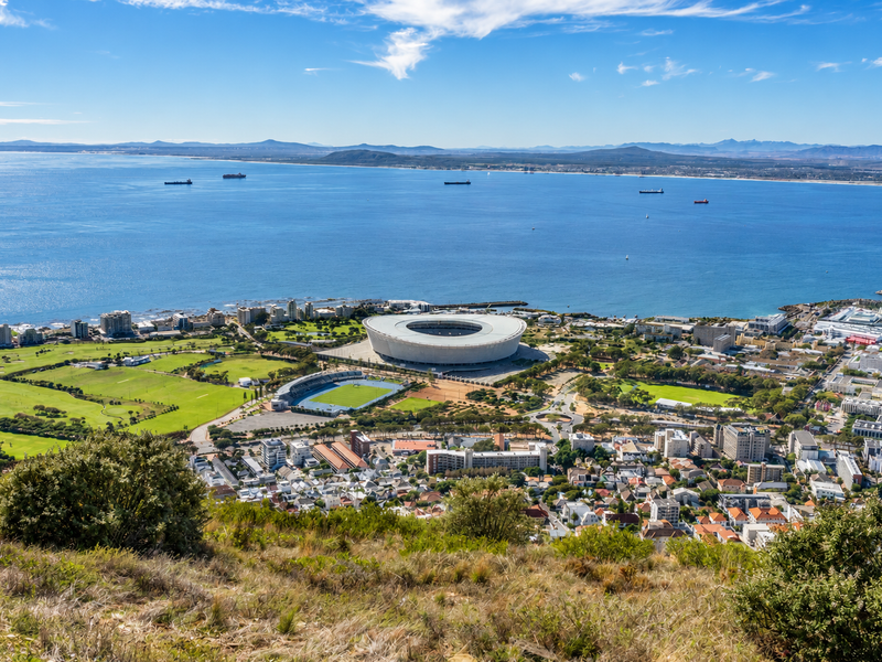 Panoramic aerial view overlooking the city, stadium, and coastline, showcasing the expansive ocean and surrounding urban landscape.
