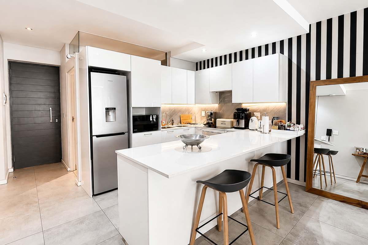 Modern kitchen featuring sleek white cabinetry, stone countertops, a functional island, and integrated appliances, complemented by contemporary tiled flooring and stylish accent wall.
