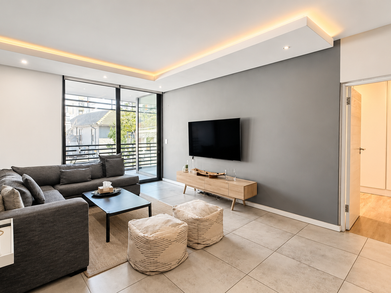 Modern living room featuring tiled floors, recessed ceiling lighting, and a large sliding glass door leading to a balcony.