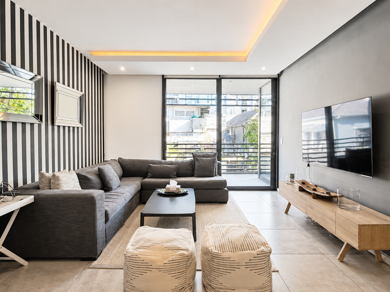 Modern living room featuring tiled floors, recessed ceiling lighting, and large sliding glass doors providing access to the balcony.