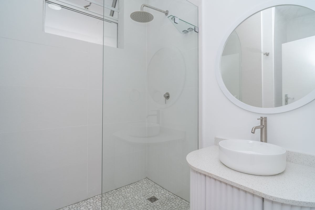 Modern bathroom featuring a walk-in shower with a rain shower head, mosaic floor tiles, and a sleek vanity with a vessel sink.
