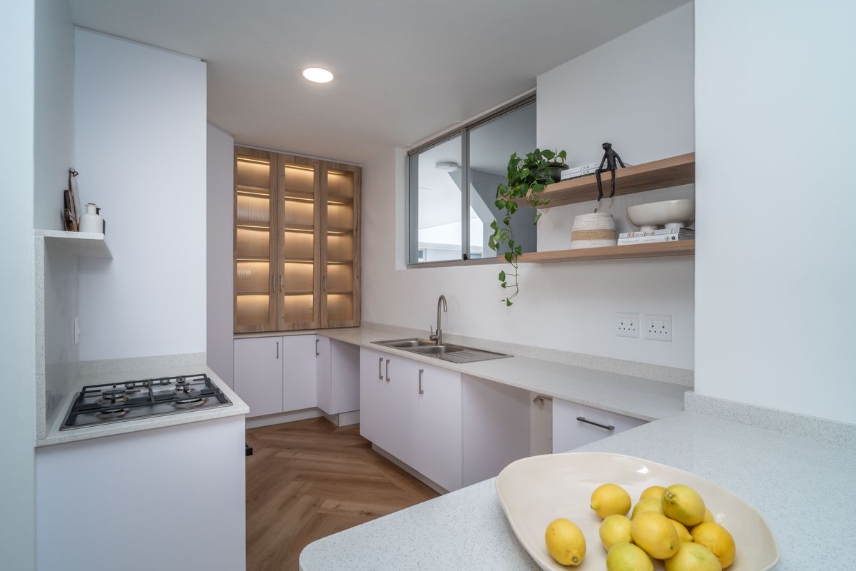 Modern kitchen featuring white cabinetry, stone countertops, a gas hob, and elegant herringbone flooring with integrated display lighting.