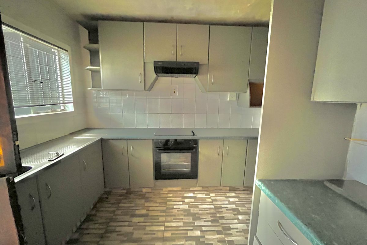 A functional kitchen featuring built-in cabinetry, an integrated oven and hob, tiled backsplash, and tiled flooring, offering a blank canvas for modern updates.