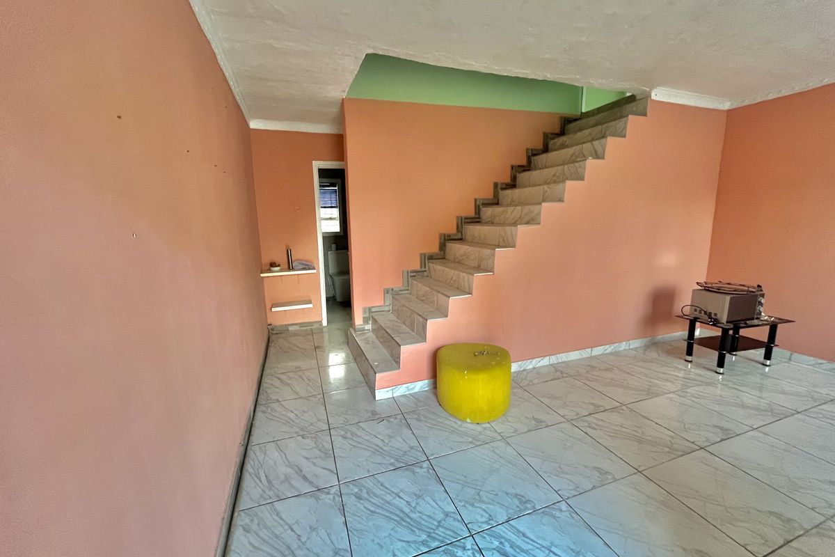 Open living area featuring ceramic floor tiles and a tiled staircase, providing a blank canvas for renovation and interior design updates.