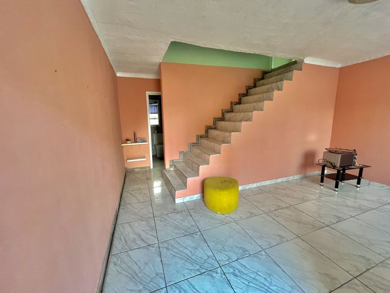 Open living area featuring ceramic floor tiles and a tiled staircase, providing a blank canvas for renovation and interior design updates.