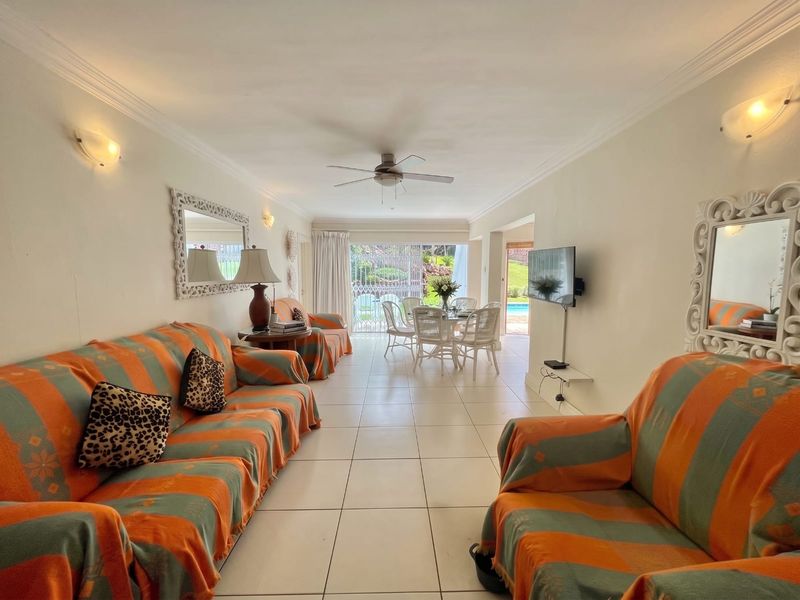 Spacious open-plan living and dining area featuring tiled floors, ceiling fan, and direct access to an outdoor patio through sliding glass doors.