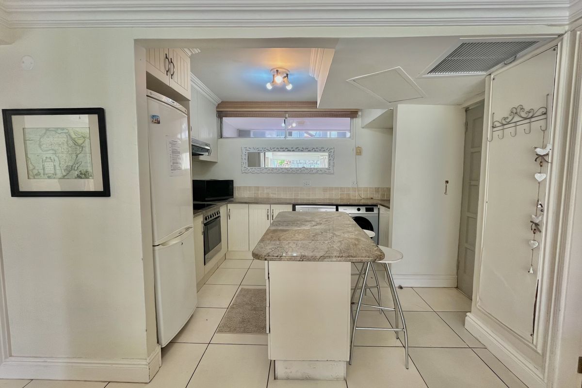 A functional kitchen featuring built-in cabinetry, a stone-topped island, and tiled flooring, offering a practical layout for cooking and casual dining.