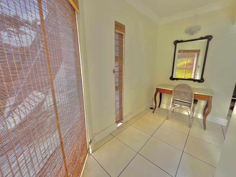 A bright hallway area featuring tiled flooring, coving, and a wall-mounted light fixture, providing a clean and functional transition space.