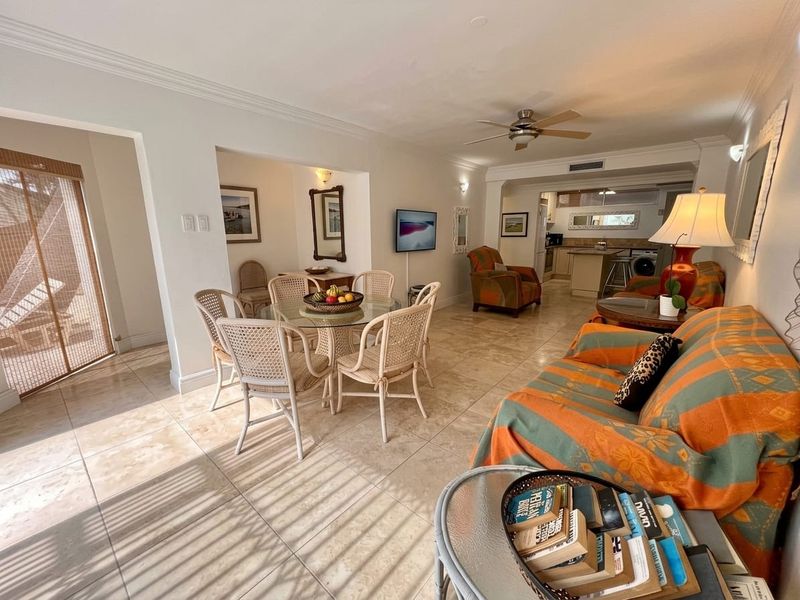 Spacious open-plan living and dining area featuring tiled flooring, a ceiling fan, and a connected kitchen with island cabinetry.