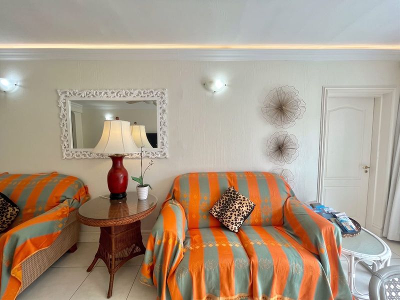 A well-lit living room featuring tiled flooring, recessed ceiling lighting, and wall sconces, providing a neutral foundation for interior design.