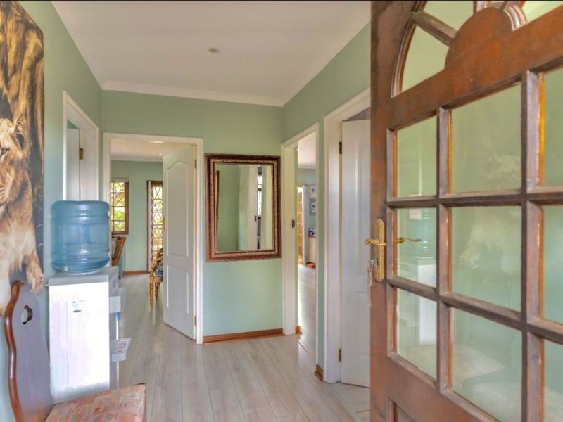 A welcoming entrance hall featuring light-toned laminate flooring, coved cornicing, and access to multiple internal rooms through classic panel doors.