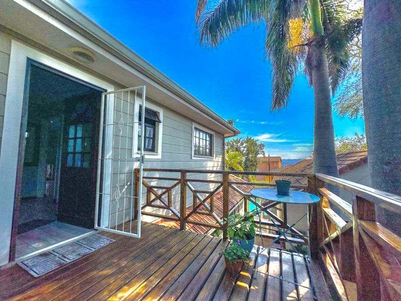 An elevated wooden balcony featuring a secure gate and balustrade, offering an outdoor space with views.