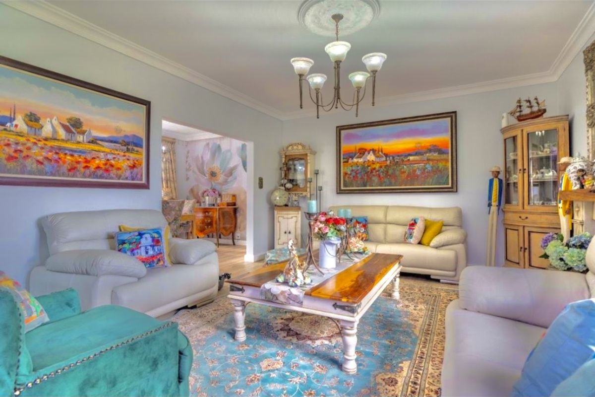 A well-maintained living room featuring a decorative ceiling rose, a classic chandelier, and elegant crown molding, creating a warm and inviting atmosphere.