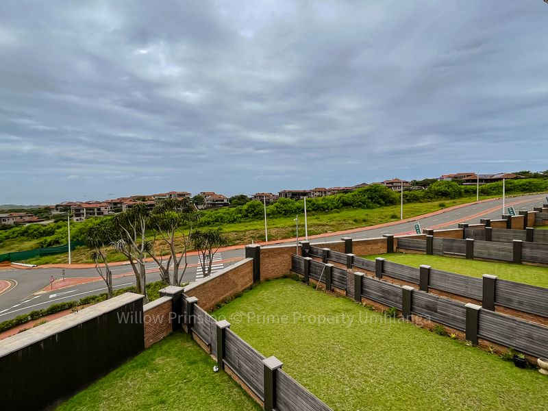 Elevated view overlooking a landscaped garden area, boundary fencing, and the surrounding residential estate road network.