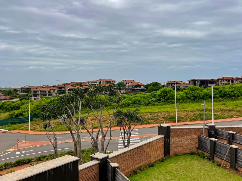 Elevated view overlooking the surrounding residential estate, featuring manicured lawns and secure boundary walling with a clear outlook of the neighbourhood.